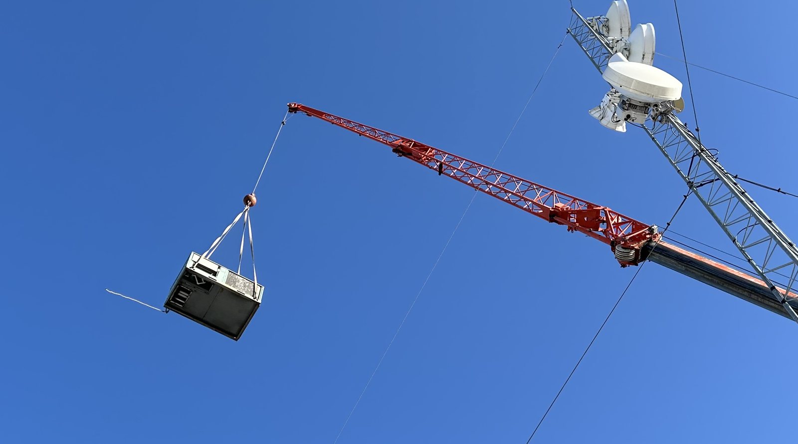 Packaged rooftop unit suspended from a crane during a changeout