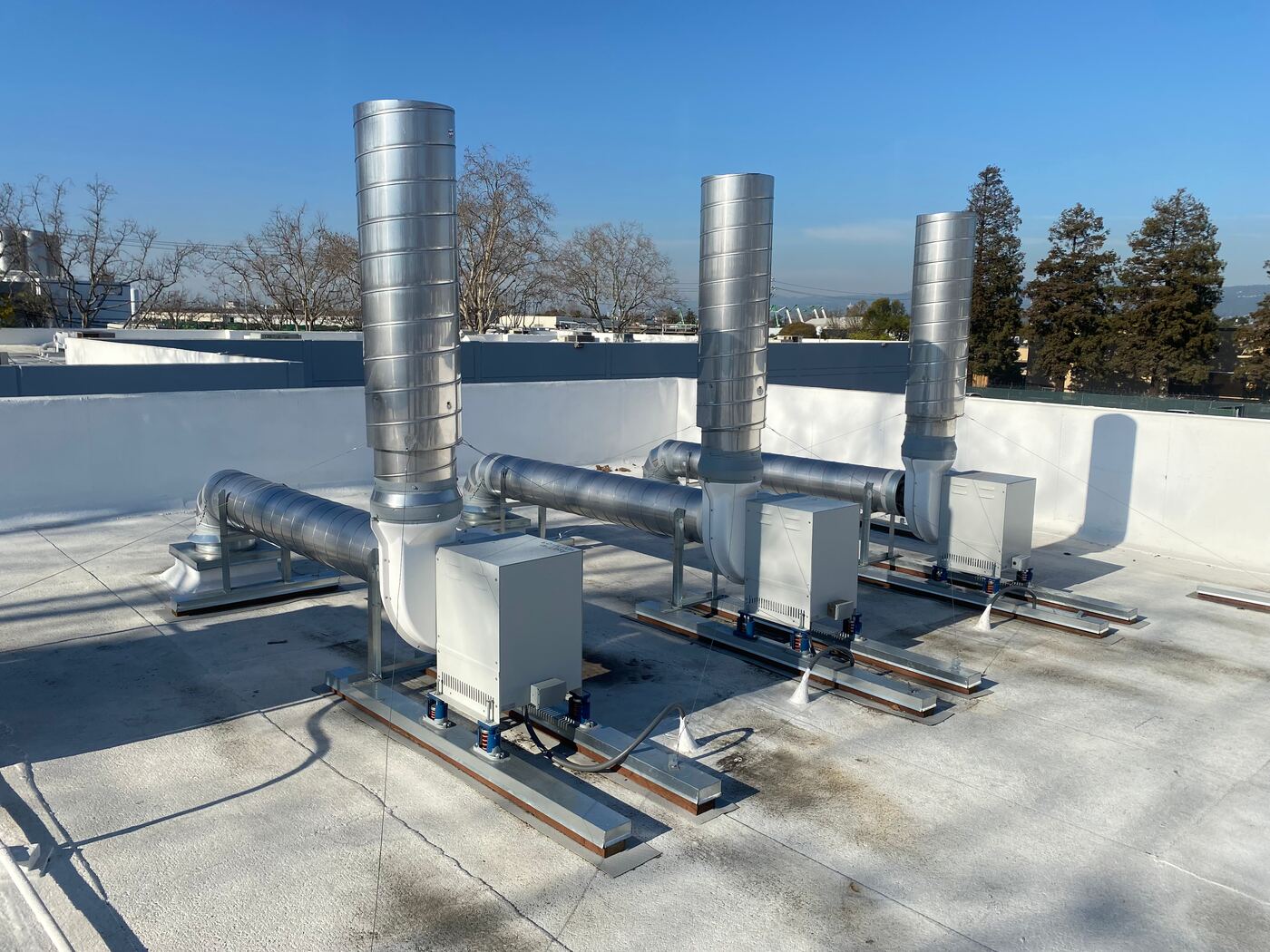 Stainless steel laboratory exhaust ductwork and fans on a commercial rooftop