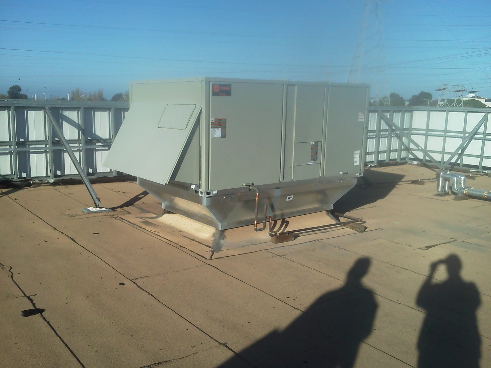 New packaged unit installed on a curb adapter behind a roof screen